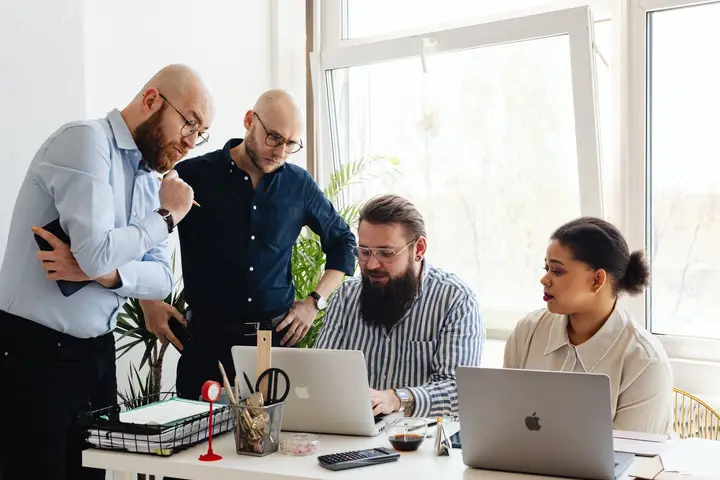 A senior consulting team reviewing a Dynamics 365 project around a laptop (sample photo)